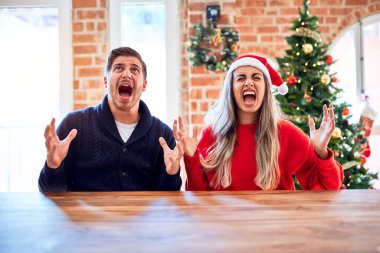 Noel Baba şapkası takan genç bir çift evde Noel ağacının etrafında oturmuş deli deli deli bağırıyor ve agresif bir ifade ve kollarla bağırıyor. Hayal kırıklığı konsepti.