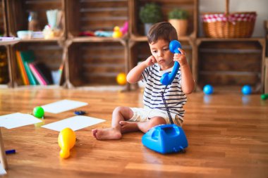 Güzel çocuk anaokulunda klasik mavi telefonla oynuyor.