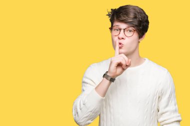 Dudaklarında parmak ile sessiz olmanı izole arka plan üzerinde gözlük takan yakışıklı delikanlı. Sessizlik ve gizli kavramı.