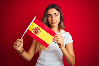 Güzel bir kadın İspanyol bayrağını kırmızı yalıtılmış arka planda tutuyor. Zeki bir yüz ifadesiyle ciddi olduğunu düşünüyor.