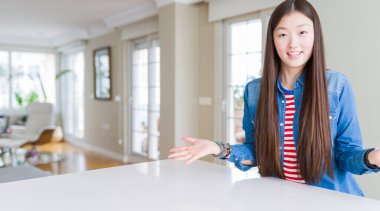 Uzun saçlı, güzel Asyalı kadın. Kot ceket giyiyor. Neşeli gülümsüyor.