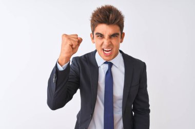 İzole edilmiş beyaz arka plan üzerinde duran takım elbiseli genç ve yakışıklı işadamı öfkeyle bağırırken kızgın ve öfkeli bir şekilde yumruk kaldırıyor. Öfke ve agresif kavram.