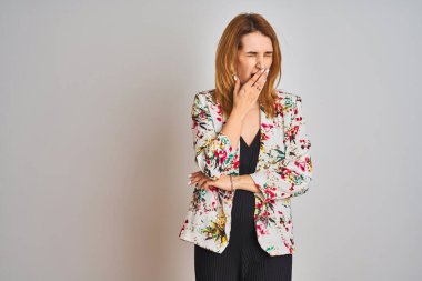 İzole bir arka plan üzerine bahar çiçeği ceketi giyen Kafkasyalı genç bir iş kadını ağzıyla esnemekten sıkılmış. Huzursuz ve uykulu..