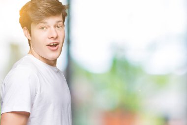 İzole arka plan korkuyor ve şok sürpriz ifade, korku ve heyecan yüz üzerinden Casual beyaz t-shirt giyen genç yakışıklı adam.
