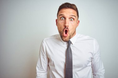 Soyutlanmış arka plan üzerinde zarif beyaz gömlek giyen yakışıklı genç bir iş adamı. Şaşırmış ve korkmuş bir ifade, korku ve heyecanlı bir yüz..