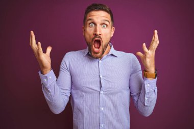 Mor izole edilmiş arka plan üzerinde zarif gömlekler giyen genç iş adamı çılgın ve başarıyı kollarını kaldırıp heyecanla haykırarak kutluyor. Kazanan konsept