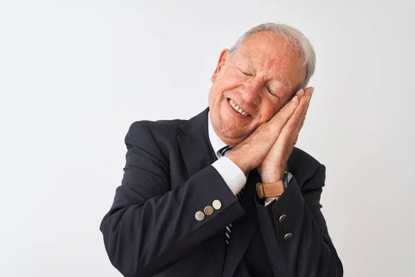 Senior grey-haired businessman wearing suit standing over isolated white background sleeping tired dreaming and posing with hands together while smiling with closed eyes.