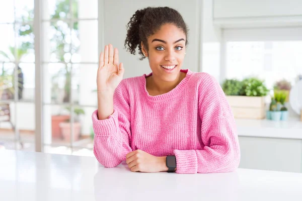 カジュアルなピンクのセーターを着てアフロの髪を持つ美しいアフリカ系アメリカ人女性こんにちは幸せと笑顔 優しい歓迎ジェスチャー — ストック写真