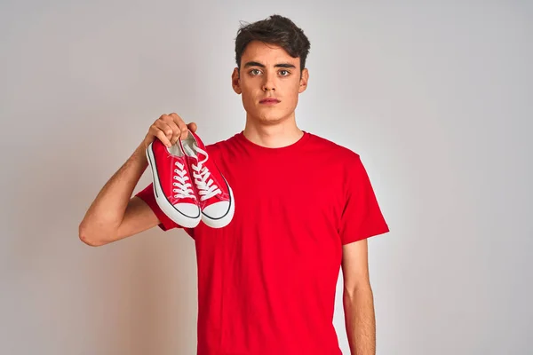 Nastolatek Trzyma Modę Luźne Tenisówki Czerwonym Odizolowanym Tle Pewnym Siebie — Zdjęcie stockowe