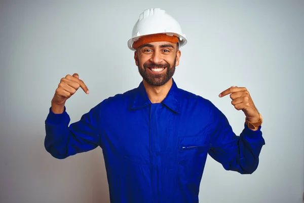 英俊的印第安工人 身穿制服 头戴安全帽 头戴白色的独立背景 面带微笑 用手指指着自己 自豪而快乐 — 图库照片