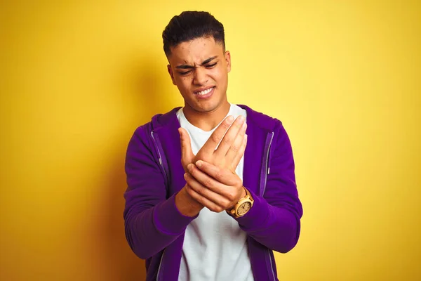 孤立した黄色の背景の上に立って紫色のトレーナーを身に着けている若いブラジル人男性手や指の痛み 関節炎の炎症 — ストック写真