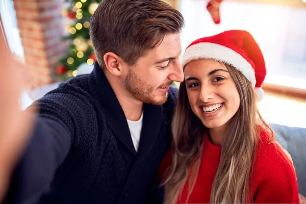 年轻漂亮的夫妇面带微笑 既快乐又自信 在家里的圣诞树前 站着用相机自拍 — 图库照片