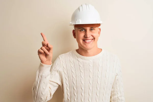 一个戴着安全帽的英俊建筑师站在孤立的白色背景上 脸上挂着大大的笑容 手指手画脚地看着摄像机的侧面 — 图库照片