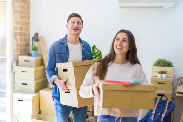 Belo jovem casal sorrindo no amor segurando caixas de papelão , — Fotografia de Stock