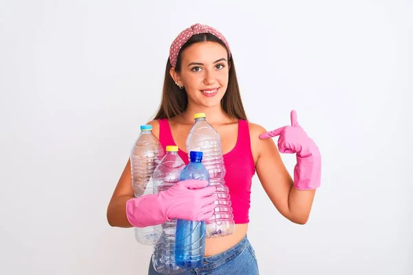 漂亮的女孩戴着干净的手套 在孤立的白色背景上回收塑料瓶 满脸惊讶地指着自己 — 图库照片