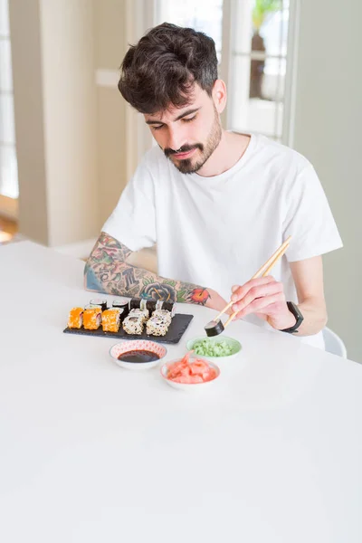 Young man eating sushi asian food using choopsticks