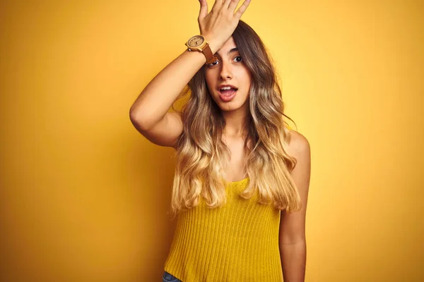 Young beautiful woman wearing t-shirt over yellow isolated background surprised with hand on head for mistake, remember error. Forgot, bad memory concept.