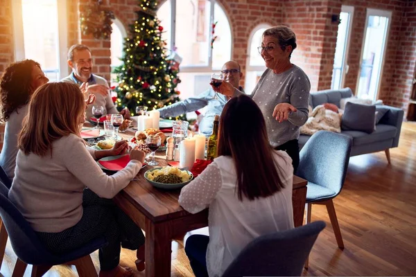 Family and friends dining at home celebrating christmas eve with traditional food and decoration, making a toast for new year best wishes