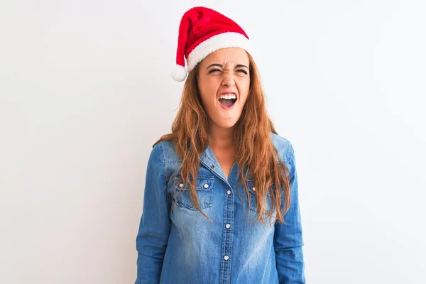 若い美しい赤毛の女性は 孤立した背景に怒りと怒りで叫んで 不満と激怒叫んでクリスマスの帽子をかぶっている 激怒と積極的な概念 — ストック写真