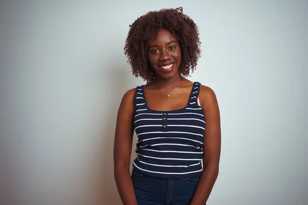 Young african afro woman wearing striped t-shirt standing over isolated white background looking away to side with smile on face, natural expression. Laughing confident.