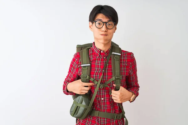 Chinese hiker man wearing backpack canteen glasses over isolated white background puffing cheeks with funny face. Mouth inflated with air, crazy expression.