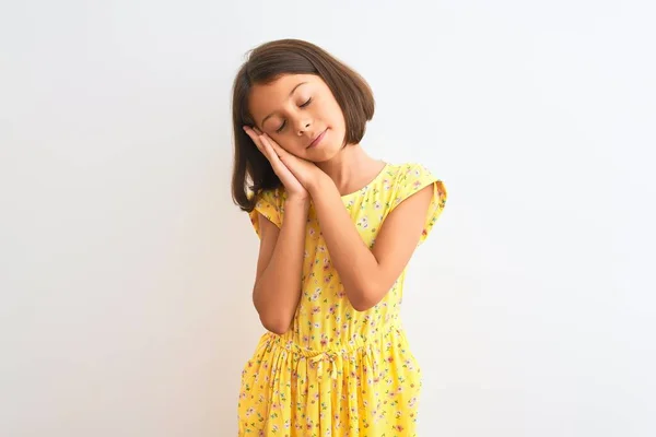 年轻美丽的小女孩穿着黄色的花衣 站在孤独的白色背景上 睡懒觉 双手合十 闭着眼睛微笑 — 图库照片