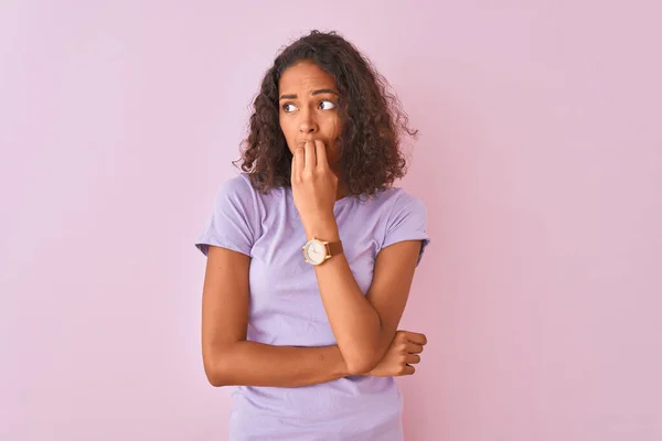 孤立したピンクの背景の上にTシャツを着た若いブラジル人女性は 口の中に爪をかむ上で手でストレスと緊張を見て立っています 不安の問題 — ストック写真