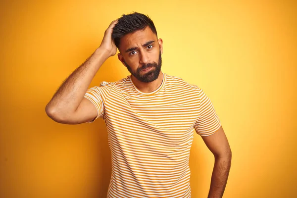 孤立した黄色の背景の上に立ってTシャツを身に着けている若いインド人男性は心配し 額に手で問題について強調しました 危機への神経と不安 — ストック写真