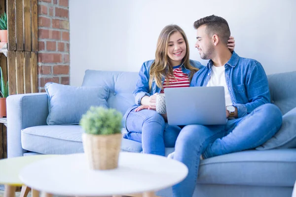 Ungt par avkopplande sitter på soffan med hjälp av datorn varv — Stockfoto