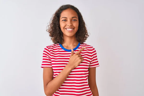 赤のストライプのTシャツを着た若いブラジル人女性が 幸せと自然な表情で顔を指差す笑顔で陽気に白い背景に立っています — ストック写真