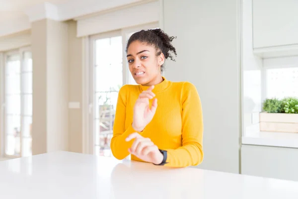 Beautiful african american woman with afro hair wearing a casual yellow sweater disgusted expression, displeased and fearful doing disgust face because aversion reaction. With hands raised. Annoying concept.