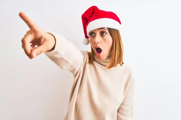 Schöne Rothaarige Frau Trägt Weihnachtsmütze Über Isoliertem Hintergrund Zeigt Mit — Stockfoto