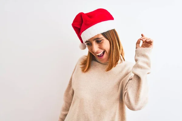 美しい赤毛の女性は孤立した背景の上にクリスマスの帽子を身に着けています幸せと陽気です 笑顔で移動カジュアルと音楽に自信を持って聞いて — ストック写真