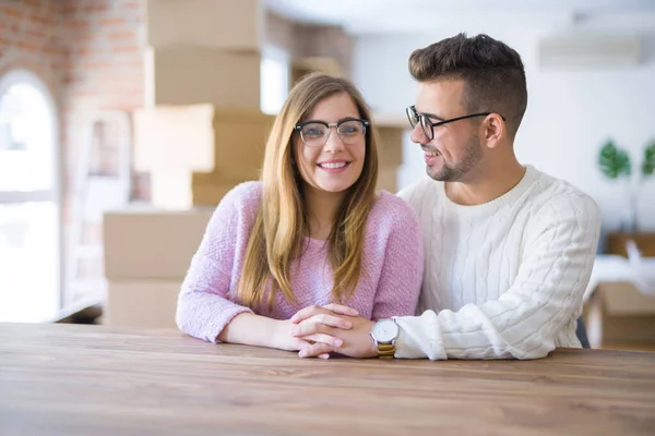 Young beautiful couple sitting on the table at home, hugging in