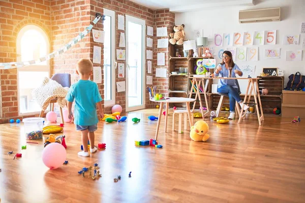 Jovem Criança Caucasiana Brincando Playschool Com Professor Jovem Sentada Mesa — Fotografia de Stock