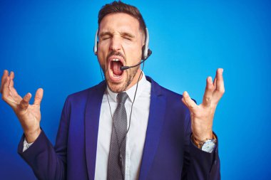 Mavi izole edilmiş arka planda çağrı merkezi kulaklığı takan genç, yakışıklı operatör kollarını kaldırmış ve gözleri kapalı heyecanla haykırarak başarıyı kutluyor. Kazanan konsept