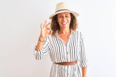 Orta yaşlı iş kadını, çizgili elbise ve şapkalı, izole edilmiş beyaz arka planda gülümseyen, el ve parmaklarıyla 