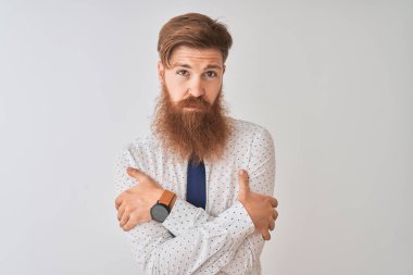 Genç kızıl saçlı İrlandalı işadamı izole edilmiş beyaz arka planda duruyor. Yüzünde üzgün ve şok ifadesiyle kış soğuğundan titriyor ve donuyor.