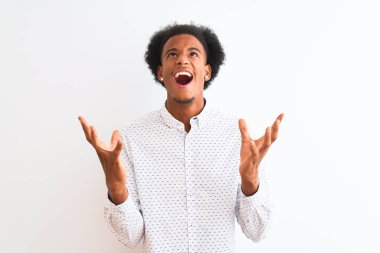 Zarif bir gömlek giyen genç Afro-Amerikalı adam izole edilmiş beyaz arka planda çılgın ve kızgın bir şekilde duruyor ve agresif bir ifade ve kollarla bağırıyor. Hayal kırıklığı konsepti.