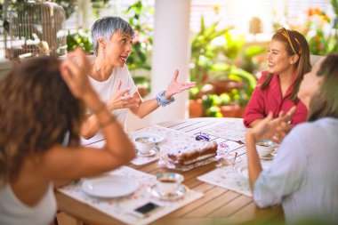 Genç ve güzel bir kız mutlu ve kendinden emin bir şekilde terasta oturmuş bir fincan kahve içiyor.