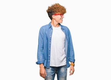 Yakışıklı genç afro saçlı gözlüklü uzak tarafına yüzünde, doğal ifade gülümseme ile seyir. Kendine güvenen gülüyor.