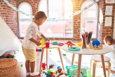 Adorable blonde twins playing around lots of toys. Cooking plastic food toy at kindergarten