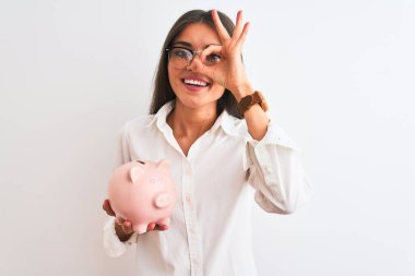 Güzel bir iş kadını gözlüklü, kumbaralı, izole edilmiş beyaz arka planda mutlu bir yüzü olan, el üstünde el işareti yapan, parmaklarının arasından bakan.