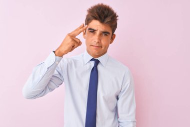 Genç yakışıklı işadamı gömlek ve kravat izole pembe arka plan Üzerinde duran Çekim ve kendini silah gibi baş el ve parmaklarını gösteren öldürme, intihar jesti.