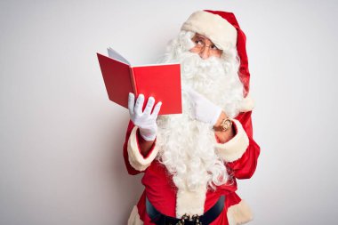 Noel Baba kostümü giyen orta yaşlı bir adam izole edilmiş beyaz arka plan üzerine kitap okuyor. Endişeli ve endişeli bir ifadeye işaret ediyor.