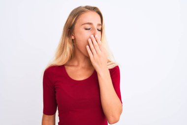 İzole edilmiş beyaz arka planda duran kırmızı tişört giyen genç ve güzel bir kadın ağzıyla esnemekten sıkılmış. Huzursuz ve uykulu..