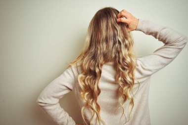 Kış balıkçı yaka kazak giyen güzel bir kadın izole edilmiş beyaz arka planda geriye doğru, elleri kafasında şüpheyi düşünüyor.