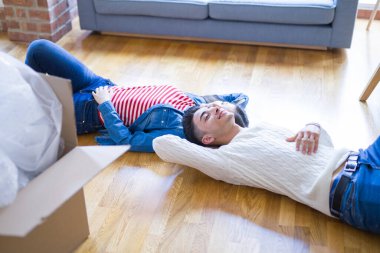 Genç Asya çift yatıyor üzerinde bu zemin bu yeni ev civarı karton kutular rahatlatıcı ve gülümseyen mutlu