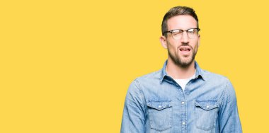 Seksi ifade, neşeli ve mutlu yüz ile kameraya bakarak göz kırparak gözlük takan yakışıklı adam.