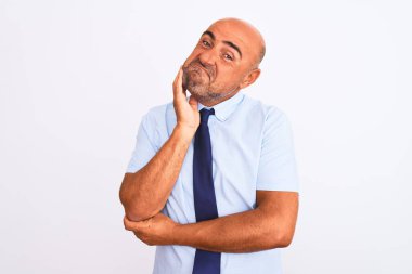 Orta yaşlı iş adamı, izole edilmiş beyaz arka planda el pençe divan duran kravat takıyor ve soru sormayı düşünüyor, düşünceli bir ifade. Düşünceli bir yüzle gülümsüyor. Şüphe kavramı.